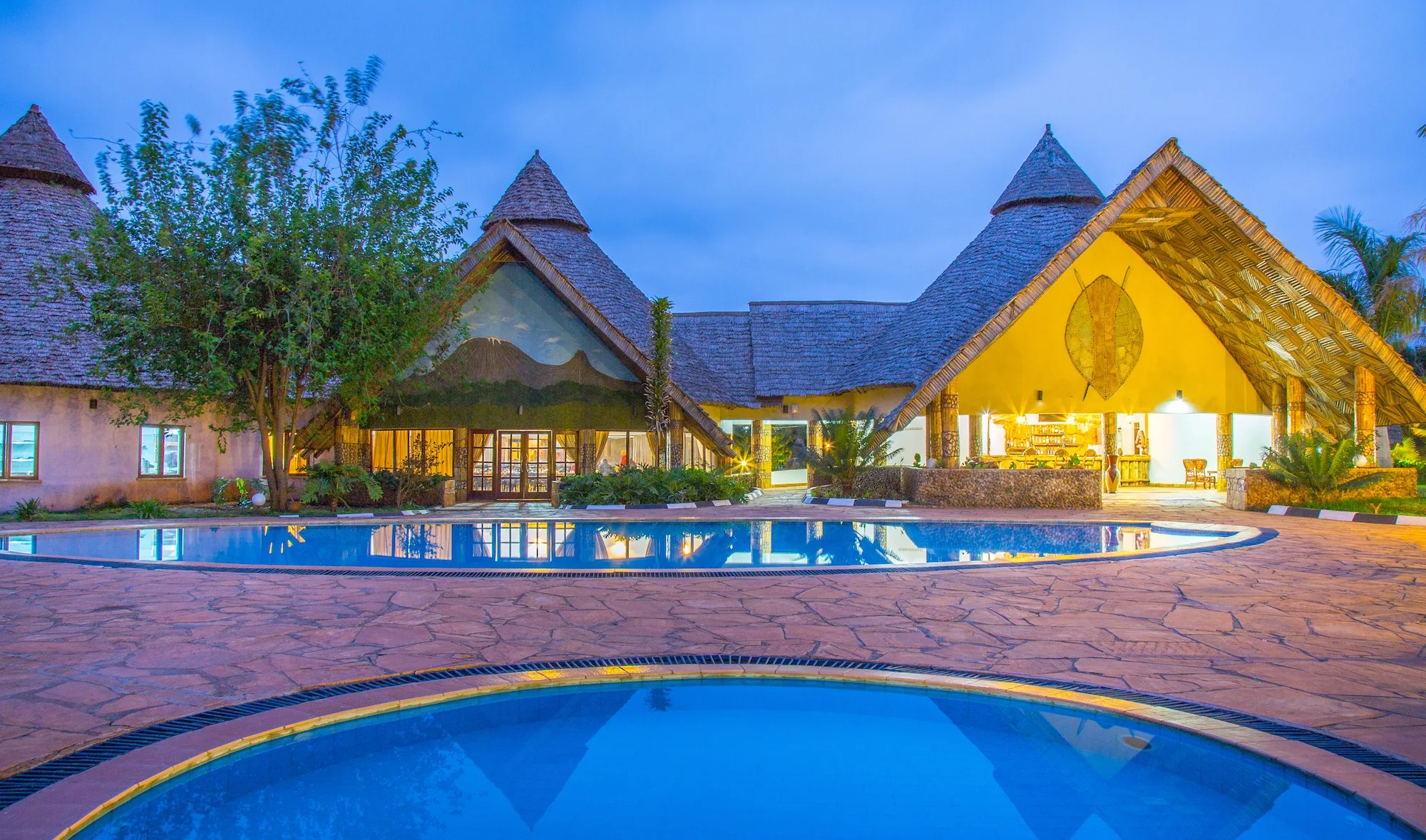 Pool and the thatched main building at dusk