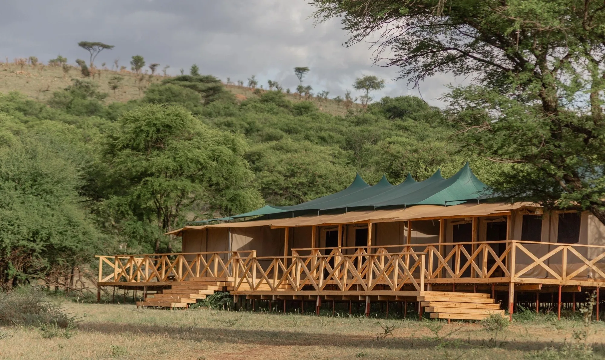 A tent on its raised deck below the hills