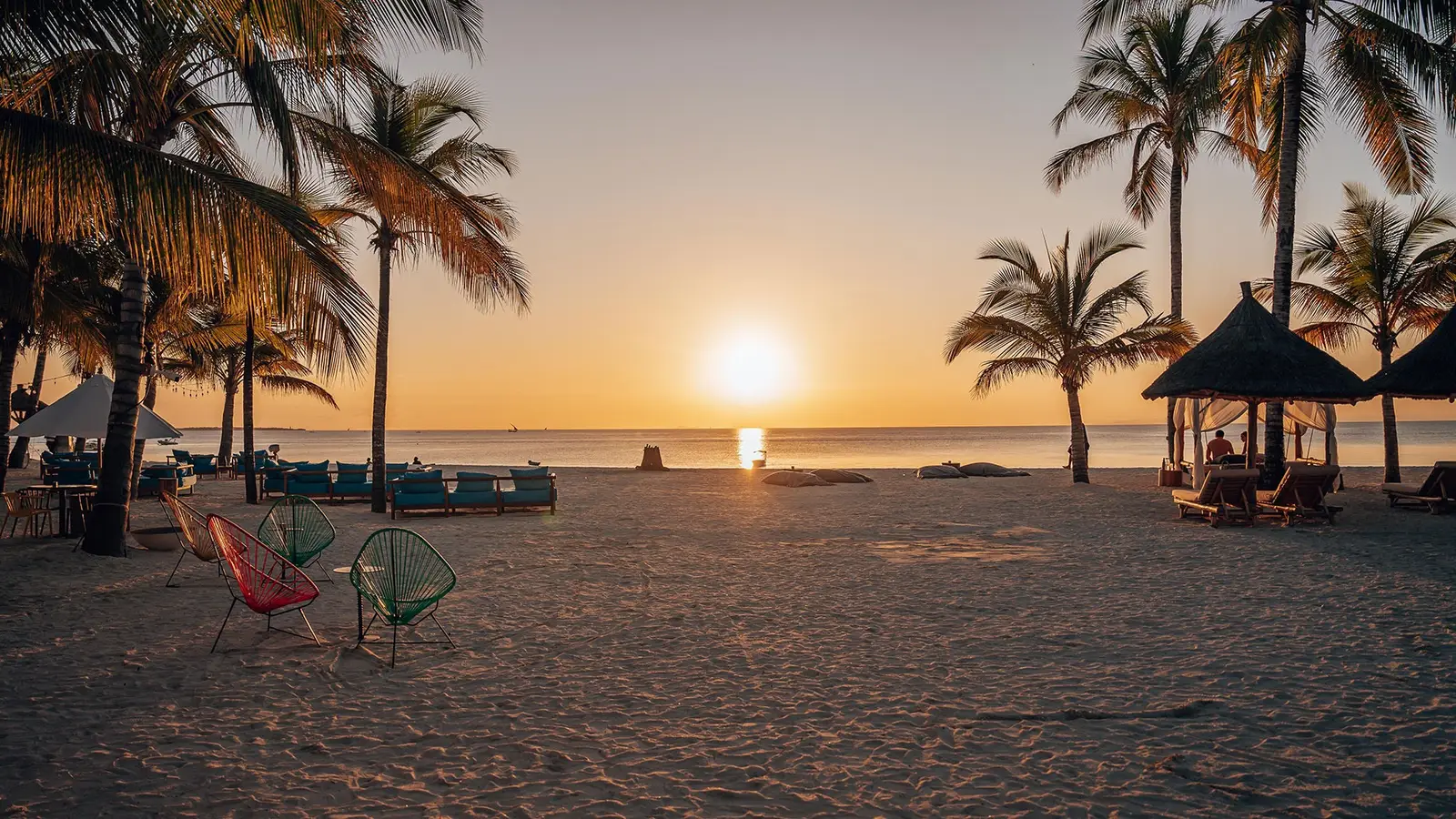 The sun setting over the Indian Ocean from Kendwa Beach, palms and loungers in silhouette